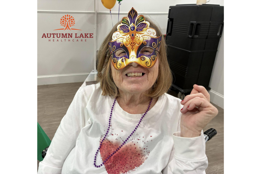 Nursing home resident smiling while wearing a festive mask.