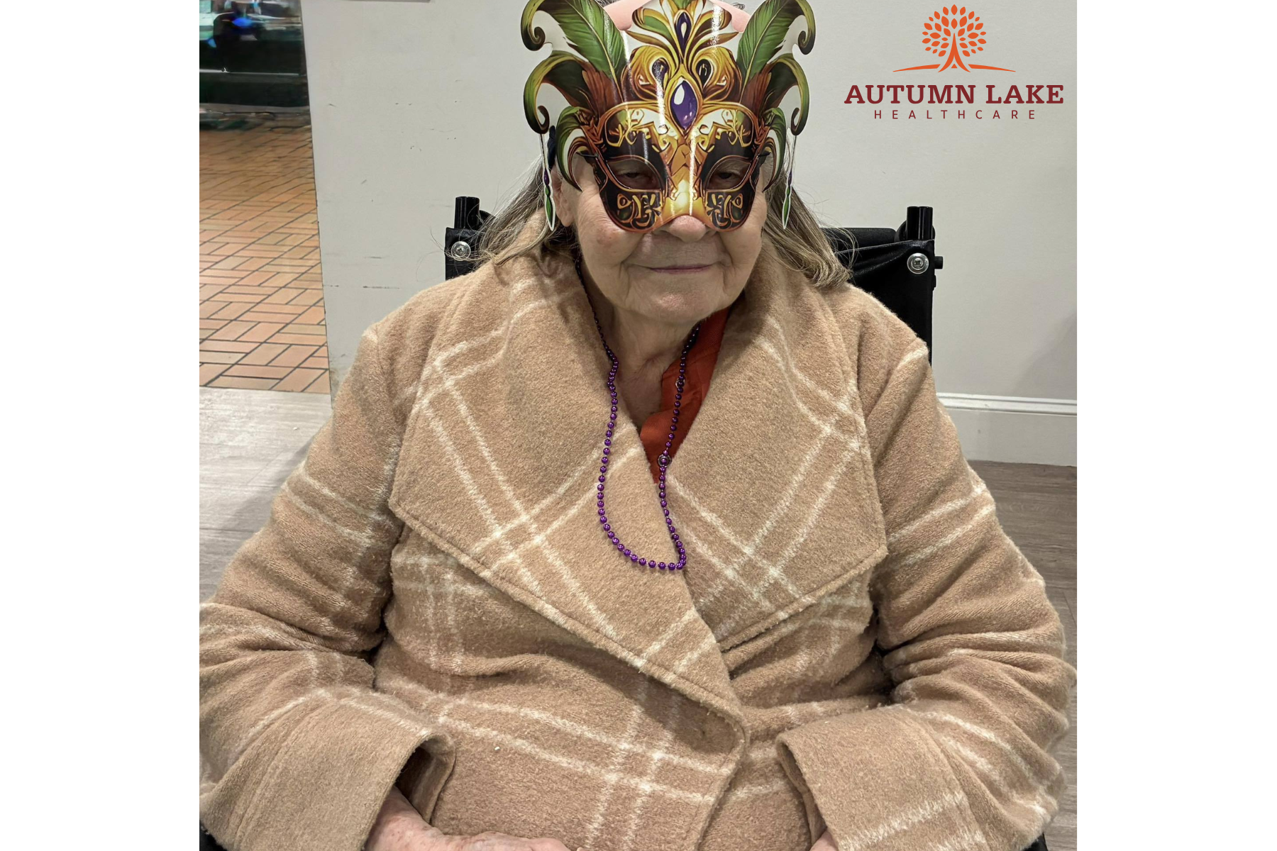 Senior in a nursing home wearing a plaid coat, purple beads, and mask